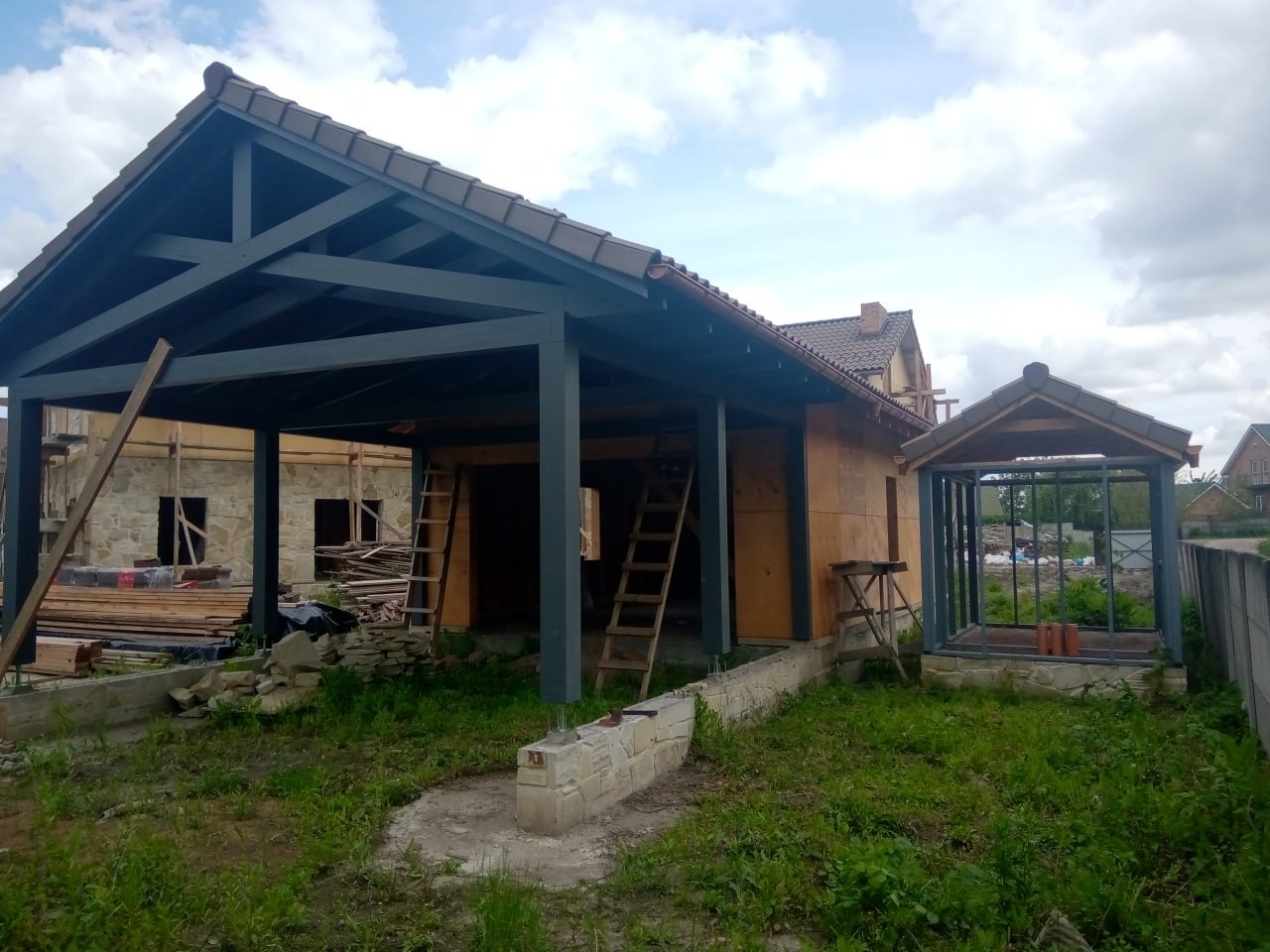 Каркасна конструкція гаража влітку: стропильна система, графітові колони, кам'яний цоколь