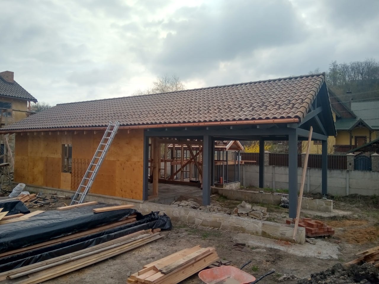 Загальний вид каркасу гаража ранньою весною з черепицею та відкритою конструкцією
